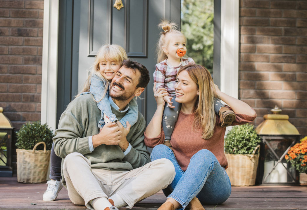 A young family sitting outside on a front porch